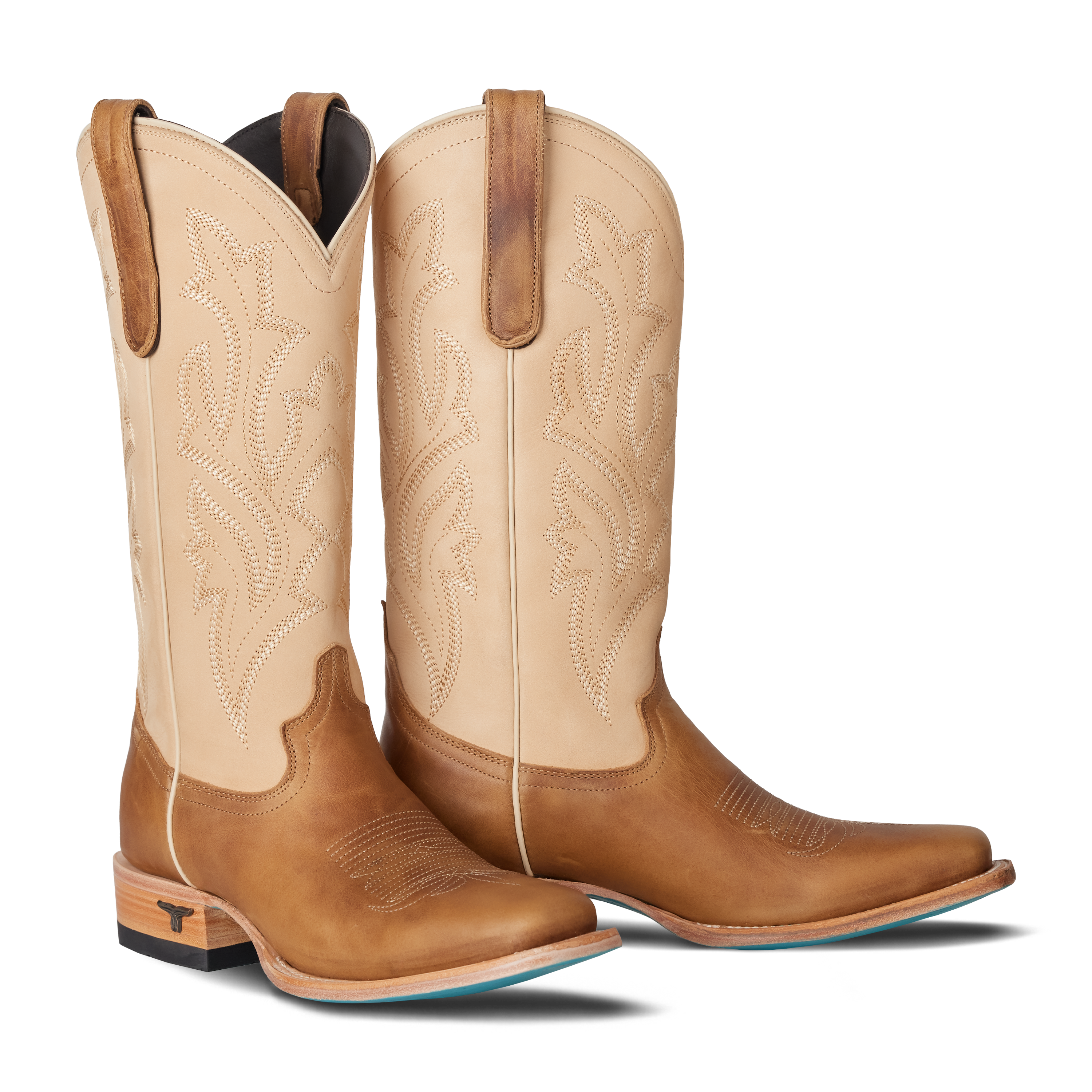 Pair of tan cowboy boots with brown accents on a white background